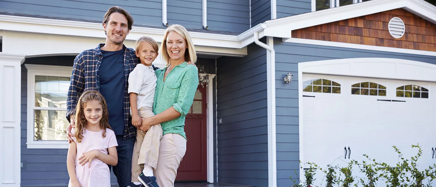 Happy family standing outside home